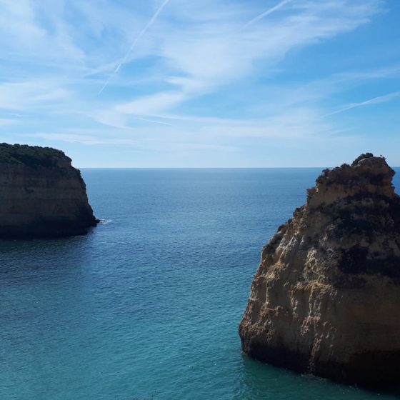 Limestone rock formations on the Algarve coast with a beautiful blue wispy sky