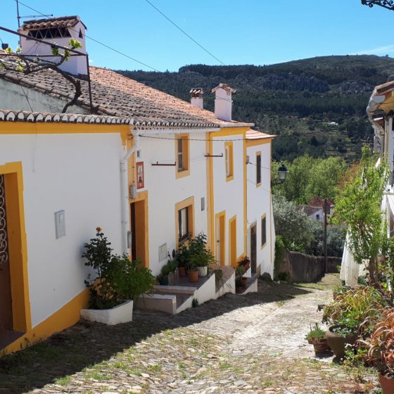 Whitewashed and yellow striped house on a cobbled lane